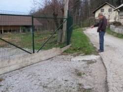 Viktor Žagar kaže, kje si meteorna voda z občinske ceste najde pot na njihovo dvorišče. (Foto: M. B. J.)
